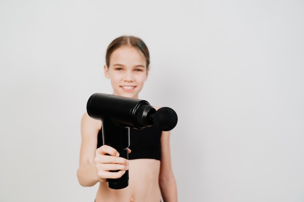 focus on subject. girl holds massage gun. medical-sports device helps to reduce muscle