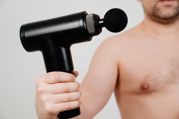 Focus on the subject. man holds massage gun.