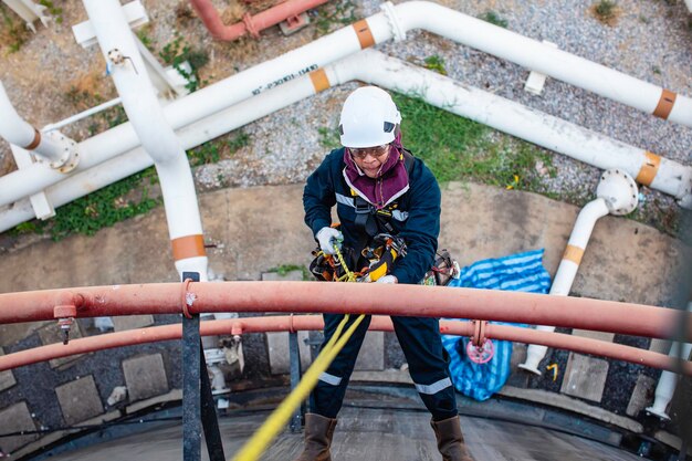 Focus top view male worker down height tank roof rope access safety inspection of thickness storage tank crude oil