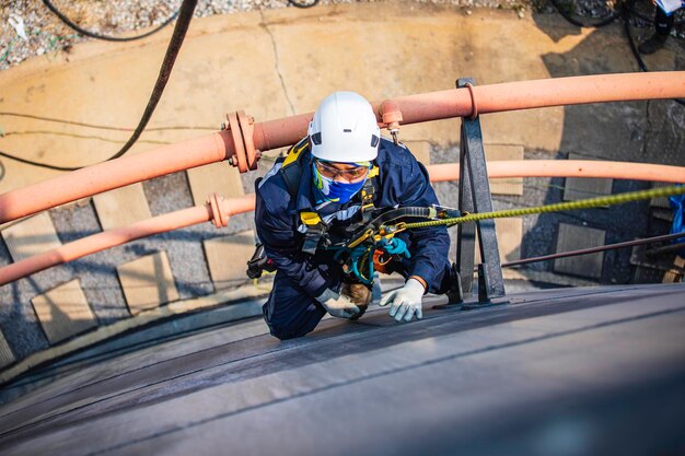 Focus top view male worker down height tank roof rope access safety inspection of thickness storage tank