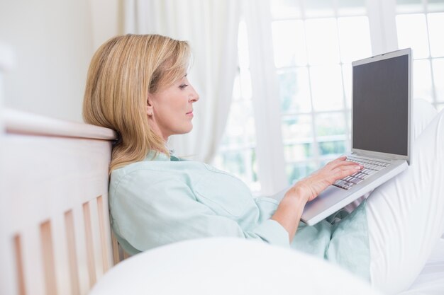 Focus woman using laptop in her bed 