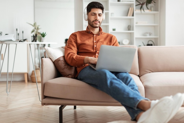 Focused arab man in headphones using pc at home