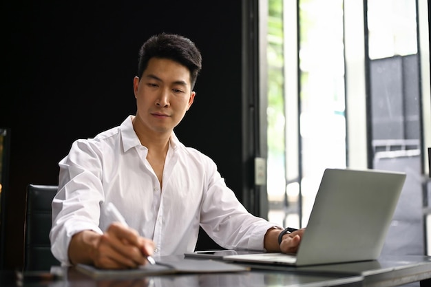 Focused Asian businessman working on his business project at his desk in the office