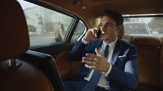 Focused business man talking on phone in interior of automobile Man in car