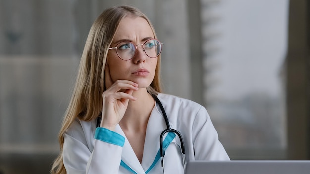 Focused caucasian female pensive nurse practitioner doctor therapist in white coat at hospital