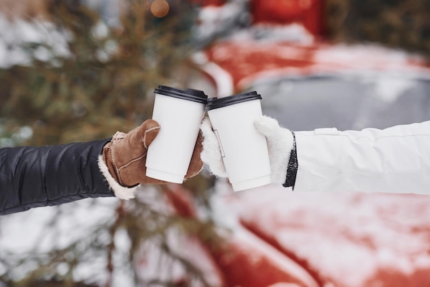 Focused close up view of women's hands that holding two cups of drink