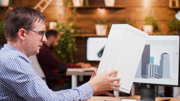 Focused engineer man analyzing building prototype developing technical construction