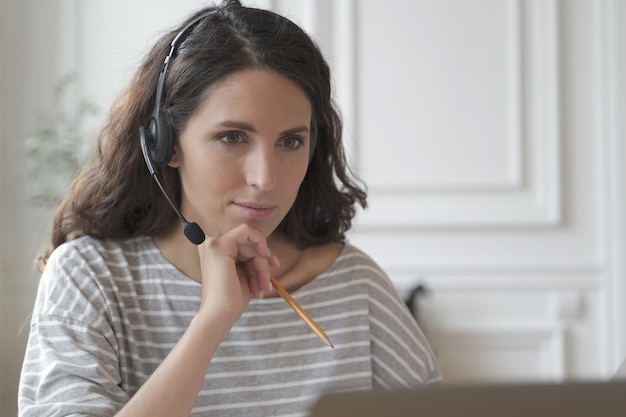 Focused entrepreneur in headphones attentively listens educational vebinar looking at laptop screen