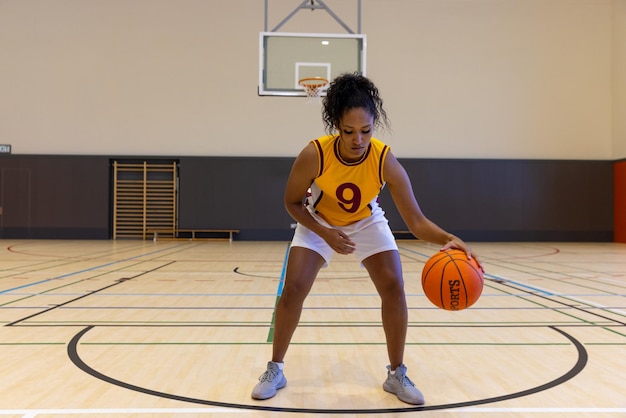 Focused female basketball player wearing sports clothes with number and playing basketball at gym. Sport, activity and lifestyle, unaltered.