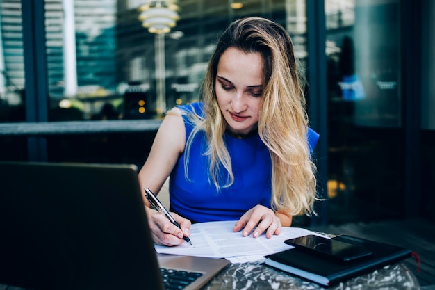 Focused female writing on documents in cafe