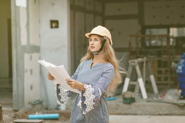 Focused lovely girl engineer in a helmet is thinking about developing a plan for building a dwalling