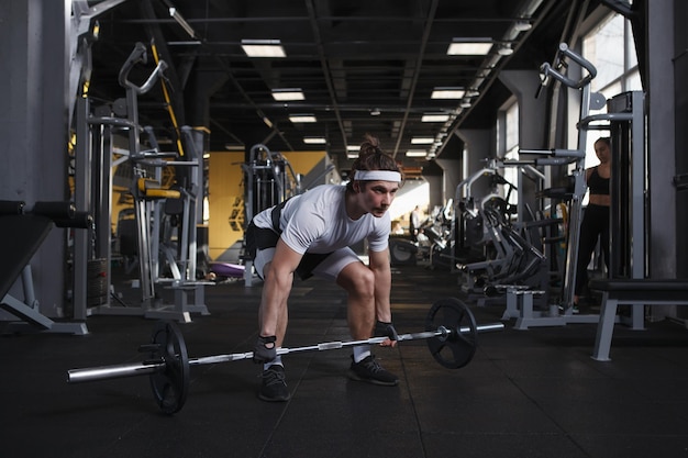 Focused male athlete doing deadlift exercise with barbell