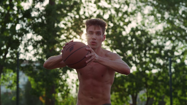 Focused muscular player practicing street basketball in sport playground