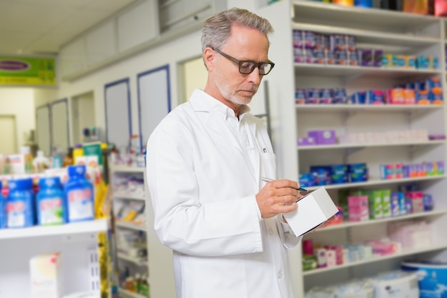 Focused pharmacist writing on box of medicine