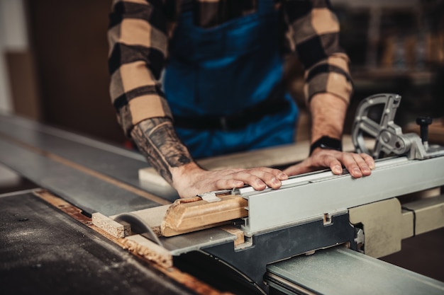 Focused professional carpenter working in his workshop, woodworking and craftsmanship concept.