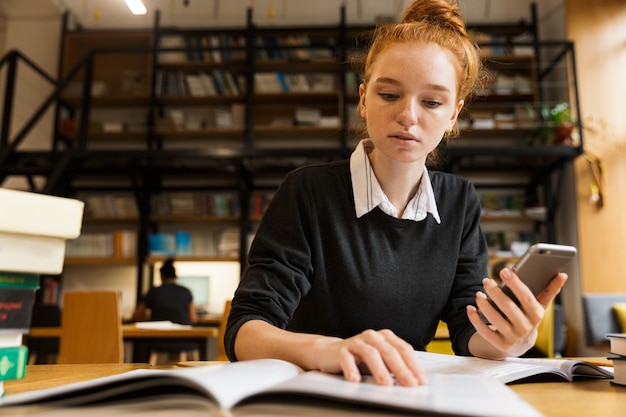 Focused red haired teenage girl studying at the table