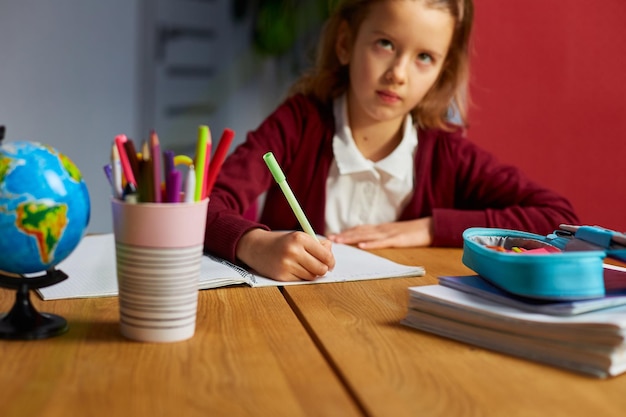 Focused schoolgirl sit at desk doing homework handwriting homeschooling