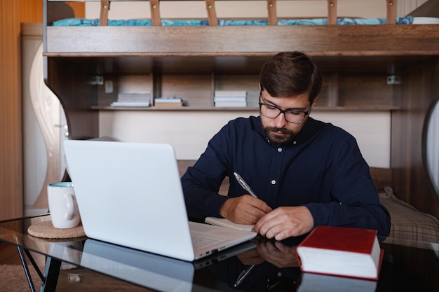 Focused serious male student using laptop looking at computer screen