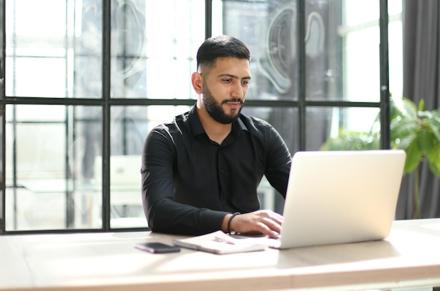 Focused young man wearing using laptop on keyboard writing email or message