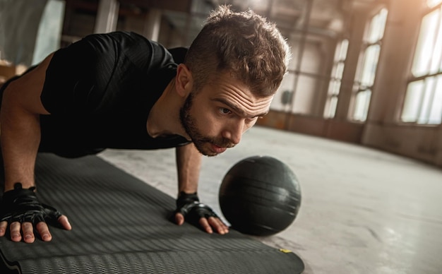 Photo focused young sportsman doing push ups in gym