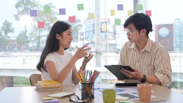 Focused young woman and her colleague are discussing new marketing strategy together