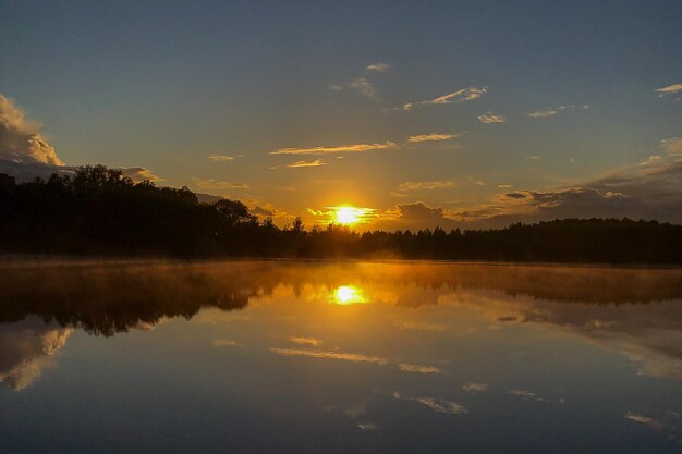 Fog over lake water surface at sunset in summer