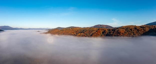 Fog among peaks of high autumn mountains with forests