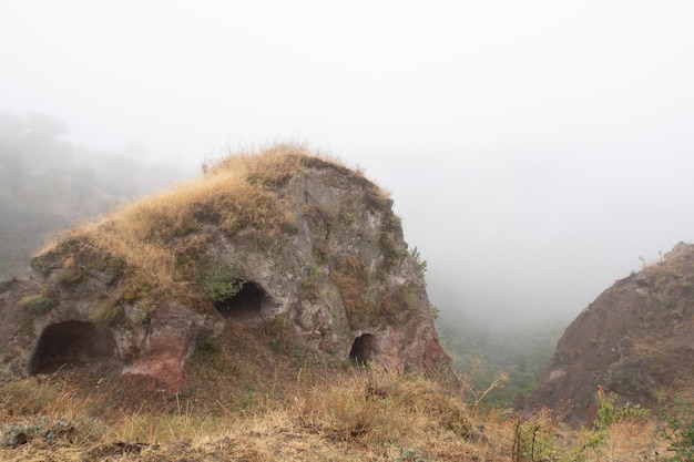 Fog view on the Khndzoresk ancient cave city in the mountain rocks Armenia landscape attraction Abandoned ruins in the mist Atmospheric stock photography