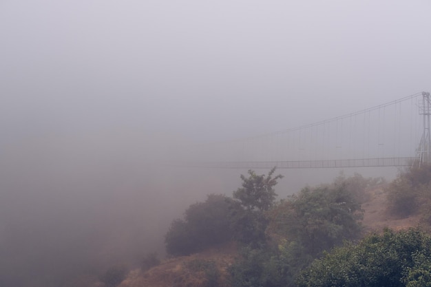 Fog view on the Khndzoresk suspension bridge in the cave city in the mountain rocks Armenia landscape attraction Abandoned ruins in the mist Atmospheric stock photo