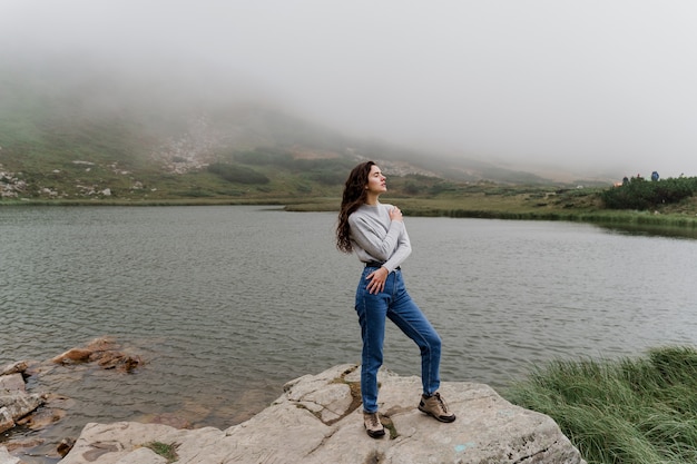 Foggy lake. Girl posing on the rocks. Lake at the peak of the mountain.