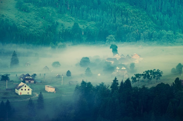 Foggy morning mountain summer landscape with mist and village