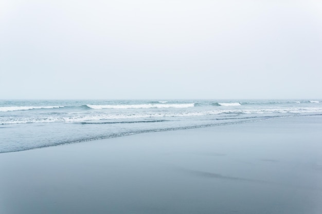 Foggy seascape cold ocean shore with a wide beach