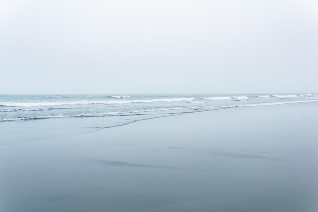 Foggy seascape cold ocean shore with a wide beach