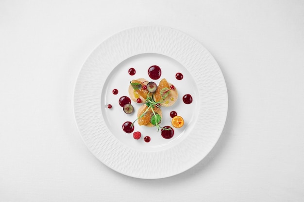 Foie gras with apple confit and berry sauce in a white plate on a white background Closeup selective focus