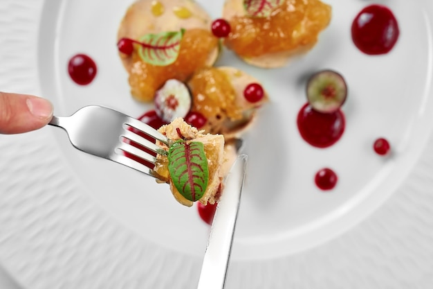 Foie gras with apple confit and berry sauce in a white plate on a white background Closeup selective focus