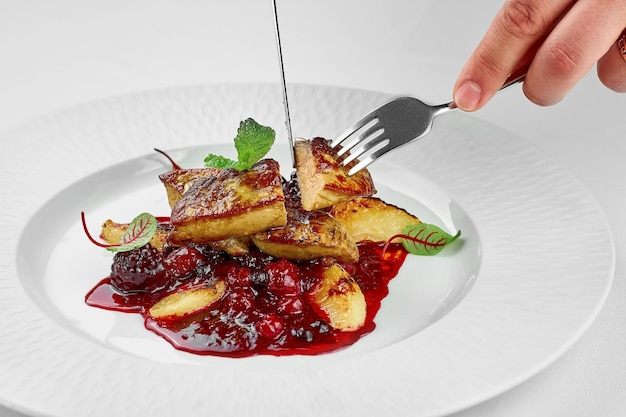 Foie gras with berry sauce on a white plate on a white plate Closeup Selective focus