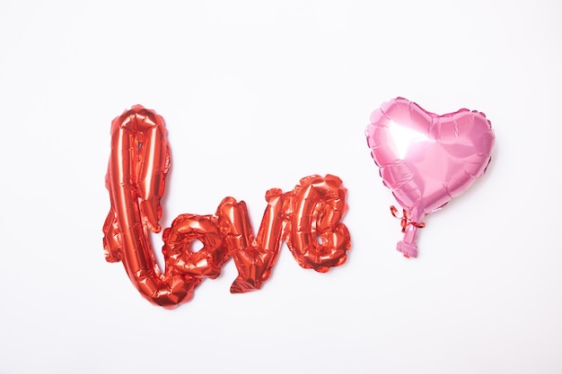 Foil balloon shape heart and love word on white background. Decorations for Valentines or Wedding Day.