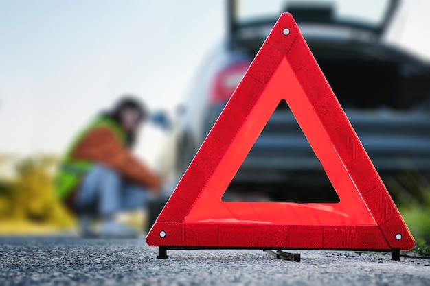 Photo fold-out warning road sign, driver changes wheel in the background