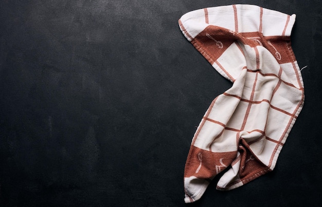 Folded linen linen kitchen towel on a black background top view