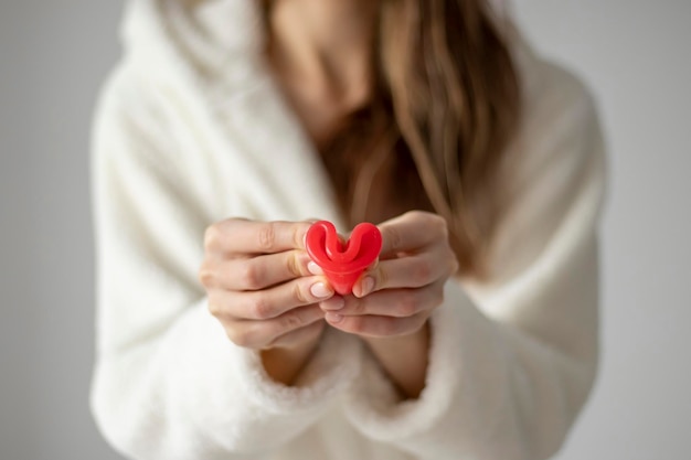 A folded menstrual cup of pink in a woman's hands Closeup selective focus