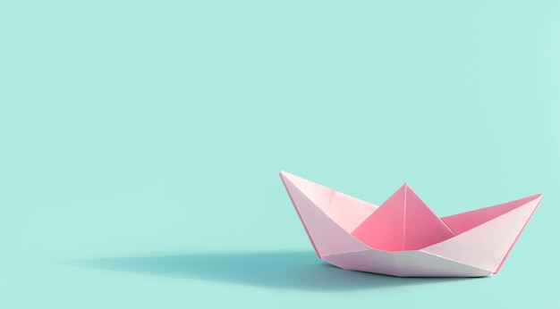 Folded paper origami pink ship on green background with shadow and  copy space