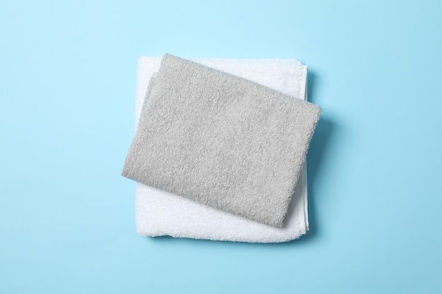 Folded towels on blue background, top view and space for text