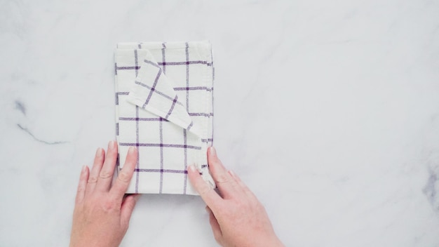 Folding blue and white patterned paper towels on marble surface.