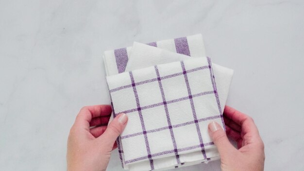 Folding blue and white patterned paper towels on marble surface.