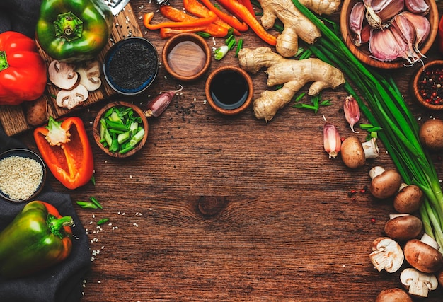 Food background Asian cuisine cooking ingredients Paprika mushrooms ginger lime garlic soy sauce and rice vinegar on wooden kitchen table Healthy eating concept Top view