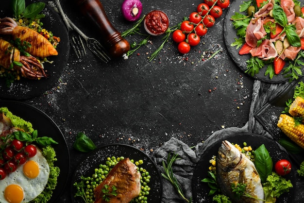 Food background Set of dishes of fish meat and vegetables on black stone background Top view Free copy space