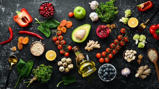 Food background A set of healthy and clean food vegetables fruits fish meat nuts and greens On a black stone background Top view Free copy space