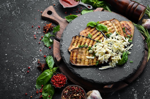 Food Baked grilled eggplant with blue cheese and basil on a black stone plate Top view Free space for your text