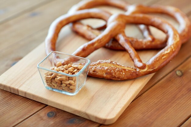 food, baking and cooking concept - close up of peanuts and pretzels on wooden table