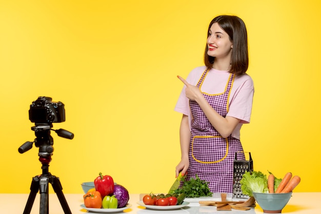 Food blogger cute lovely chef in pink apron recording video for social media pointing up